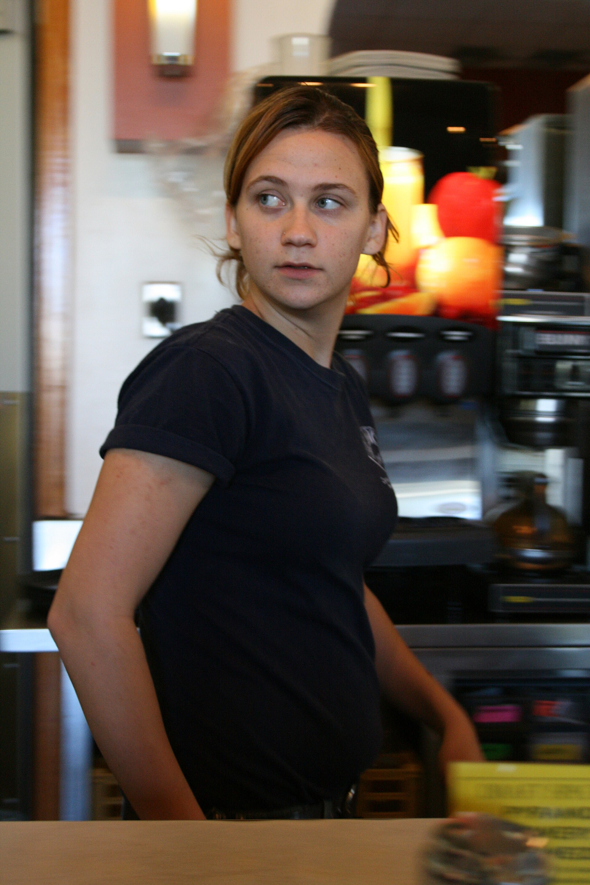 A waitress carrying plates behind the counter of a busy American diner