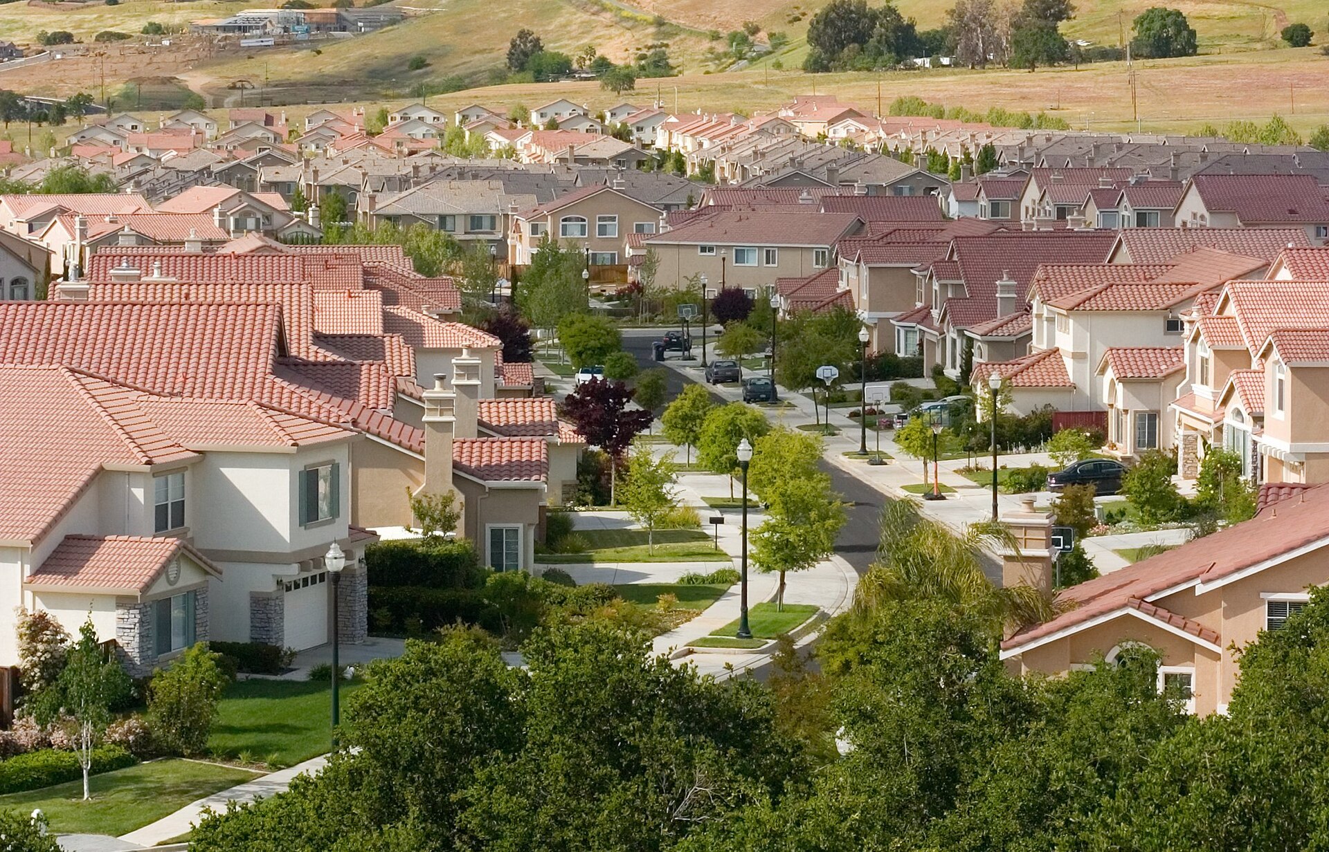 Rooftops of a vast American suburb stretching to the horizon, single-family houses in every direction